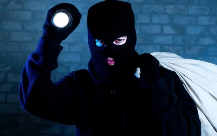 Burglar with a flashlight looking for what can be stolen.